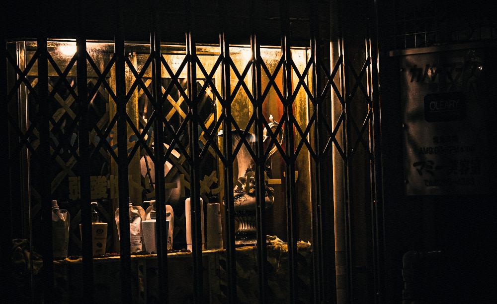 A shop window still lit behind a locked security gate at night.